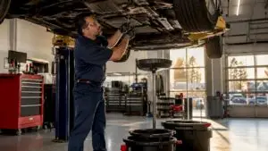 Technician removing oil drain plug during oil change