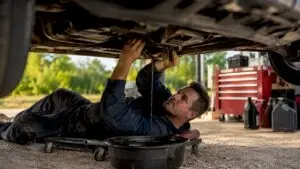 Mechanic changing SUV engine oil in garage