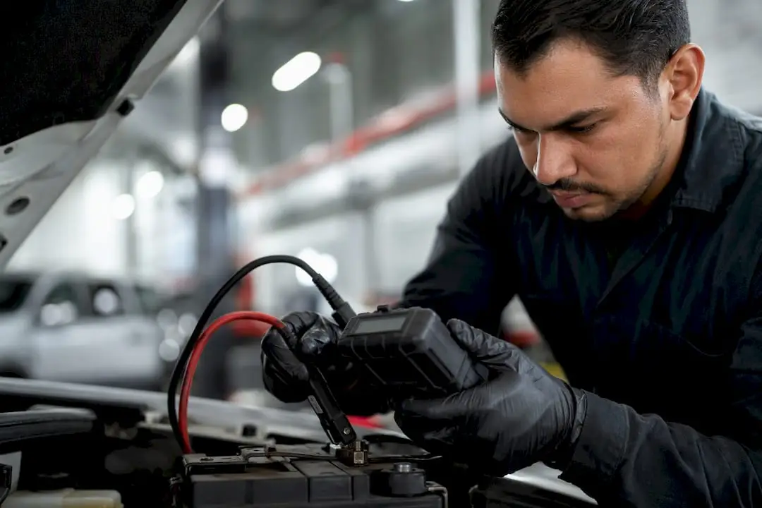 Hands testing car battery with device
