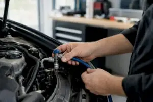 Technician connecting AC recharge hose to car