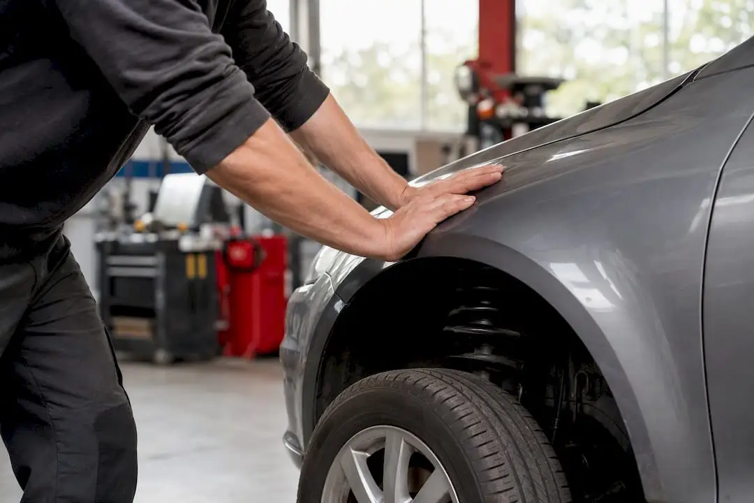 Hands performing car suspension bounce test