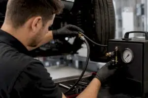 Hands connecting smoke test machine to vehicle