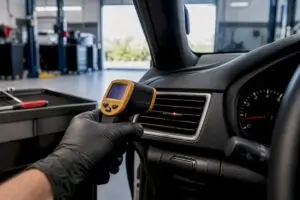Technician measuring car AC vent temperature