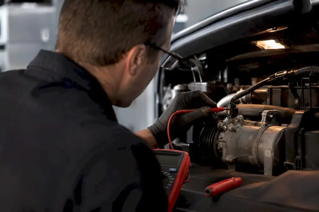 Technician testing AC compressor clutch wiring