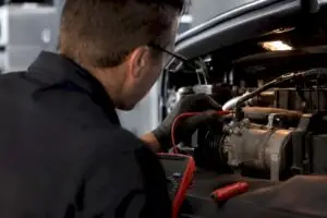 Technician testing AC compressor clutch wiring
