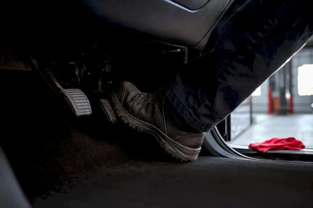 Driver testing brake pedal in service bay