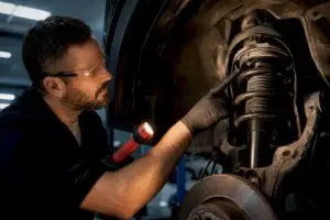 Technician inspecting exposed shock and strut assembly