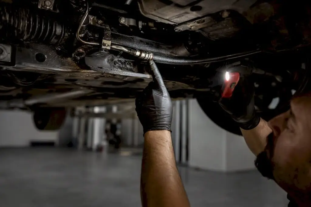 Technician inspecting steering hose for leak