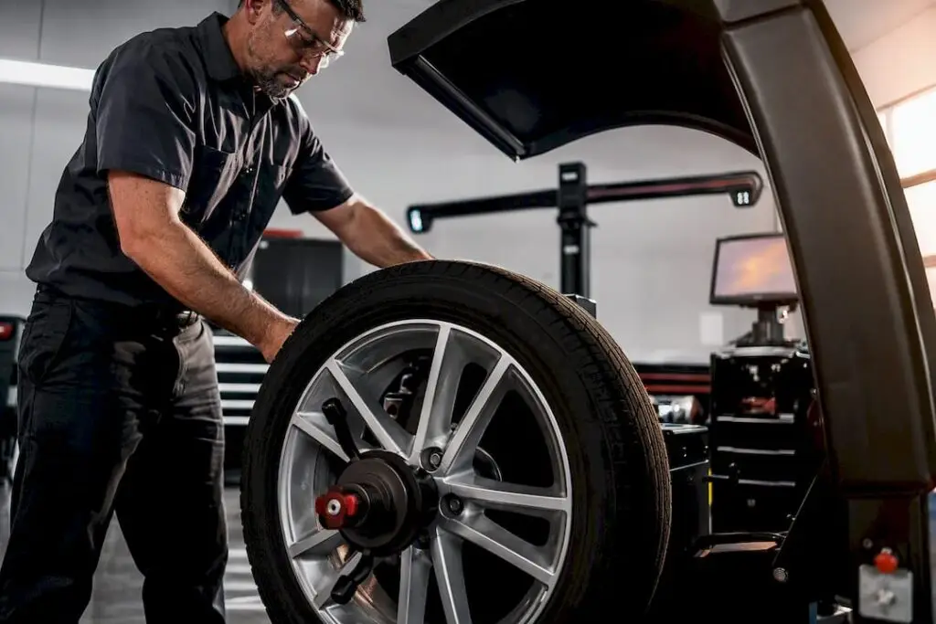 Technician servicing anonymous wheel on balancer