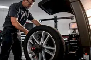 Technician servicing anonymous wheel on balancer