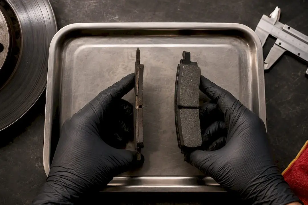 Technician comparing worn brake pad thickness