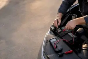 Hands testing battery drain with multimeter