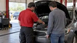 Buyer reviewing used car inspection with technician